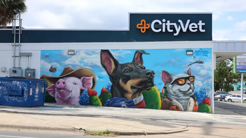 Mural colorido con animales sobre la fachada de un establecimiento veterinario en la calle.