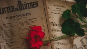 Partitura antigua con una flor roja sobre papel desgastado por el tiempo.
