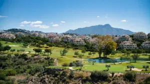 Vista panorámica de un campo de golf en Marbella con montañas al fondo.