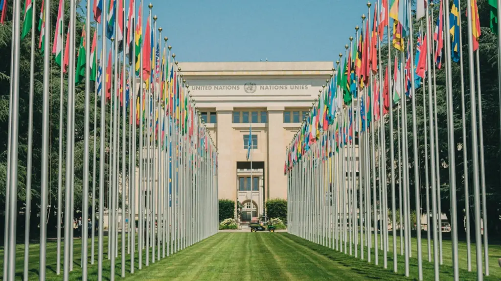 Vista frontal del Palacio de las Naciones de la ONU rodeado por muchas banderas.