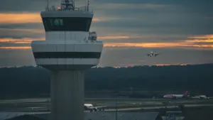 Torre de control aérea en un aeropuerto con un avión aproximándose al aterrizaje.