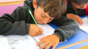 Un niño concentrado escribe en su cuaderno durante una jornada escolar en Martos.