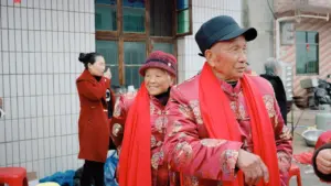 Pareja de mayores con vestimenta tradicional sonriendo durante un evento comunitario al aire libre.