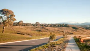 Carretera asfaltada recién construida rodeada de colinas y vegetación en un entorno despejado.