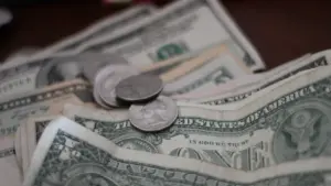 Monedas y billetes de dólar americano sobre una superficie oscura para temas financieros.
