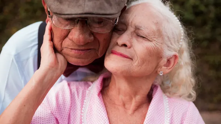 Una pareja de ancianos se abraza tiernamente evocando recuerdos de un pasado compartido.