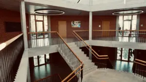 Interior moderno de un centro educativo con escalera de caracol y paredes de ladrillo.